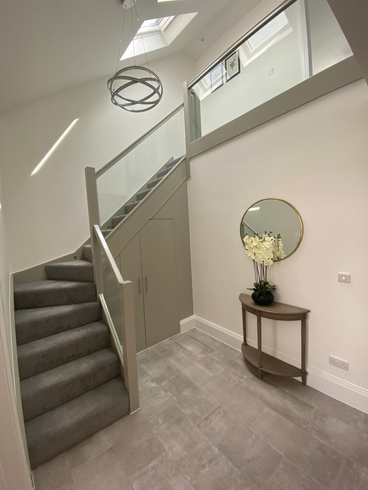 Loft conversion hallway with new staircase, glass balustrade and rooflights