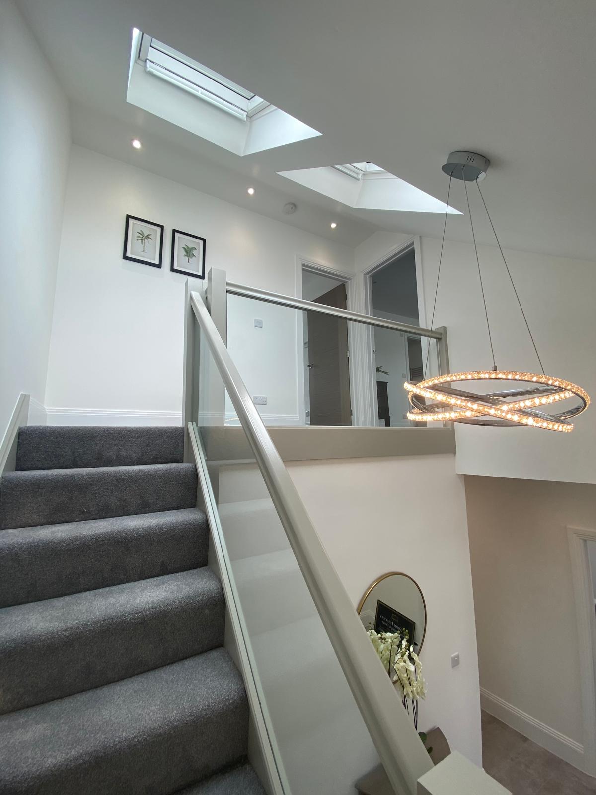 Loft landing with glass balustrade, pendant lighting and Velux rooflights
