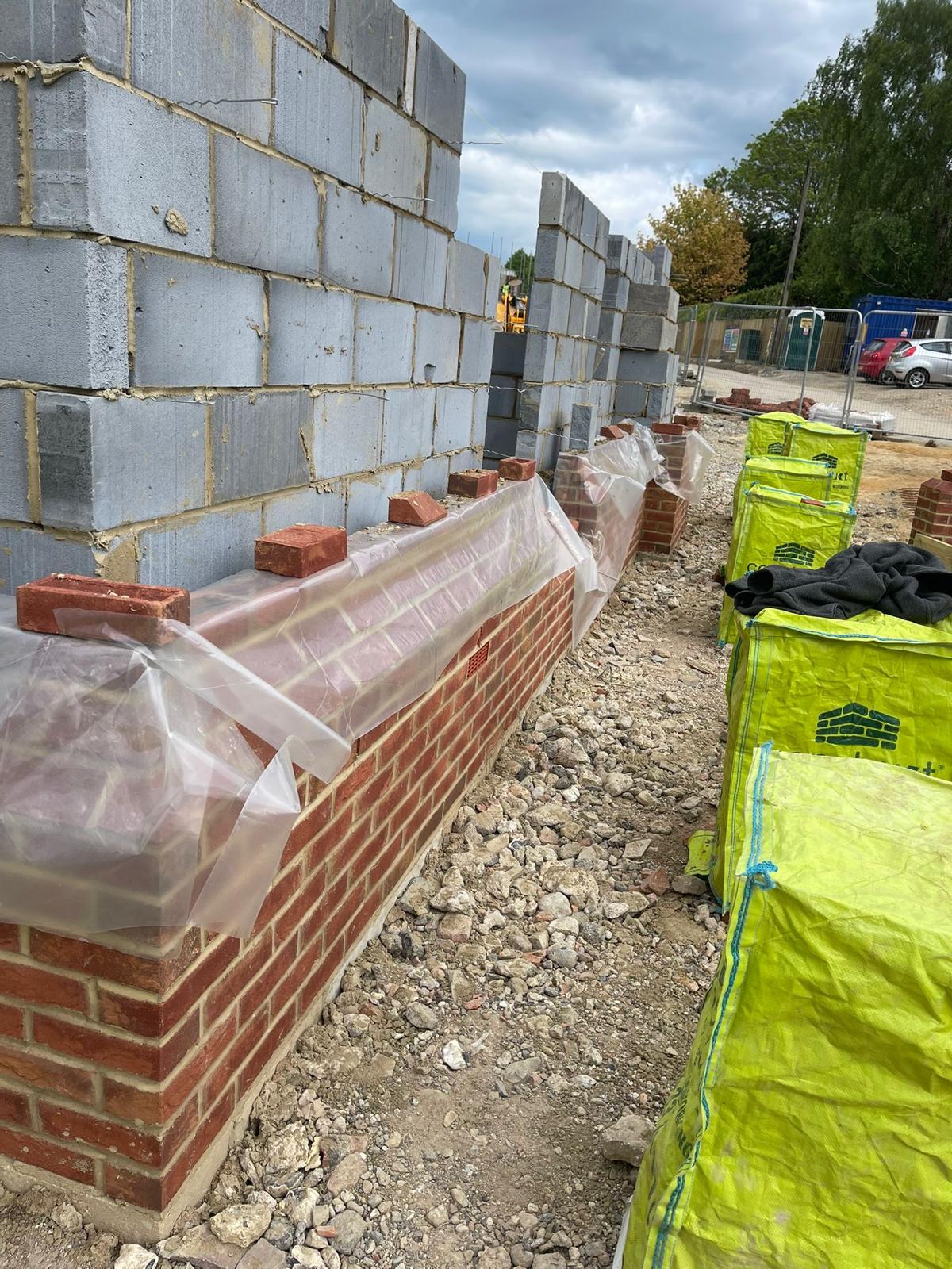 Cavity wall progressing above the brick plinth, weather-covered
