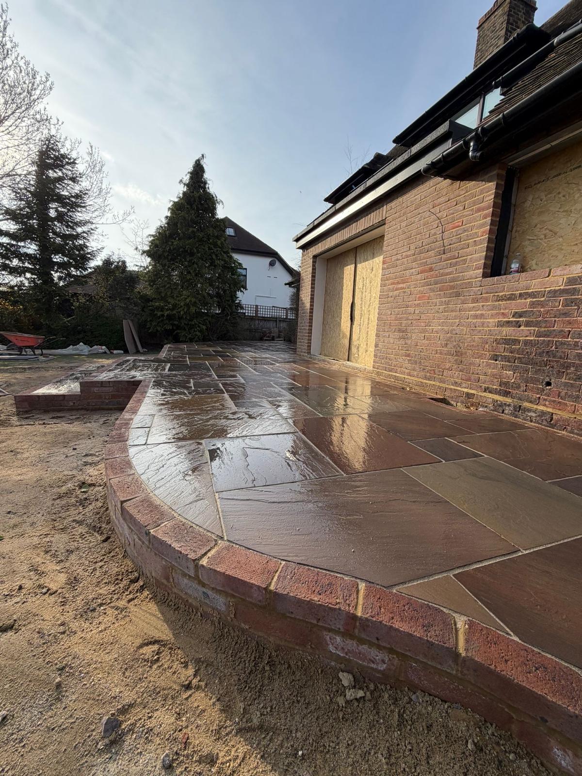 Curved sandstone patio with brick edging