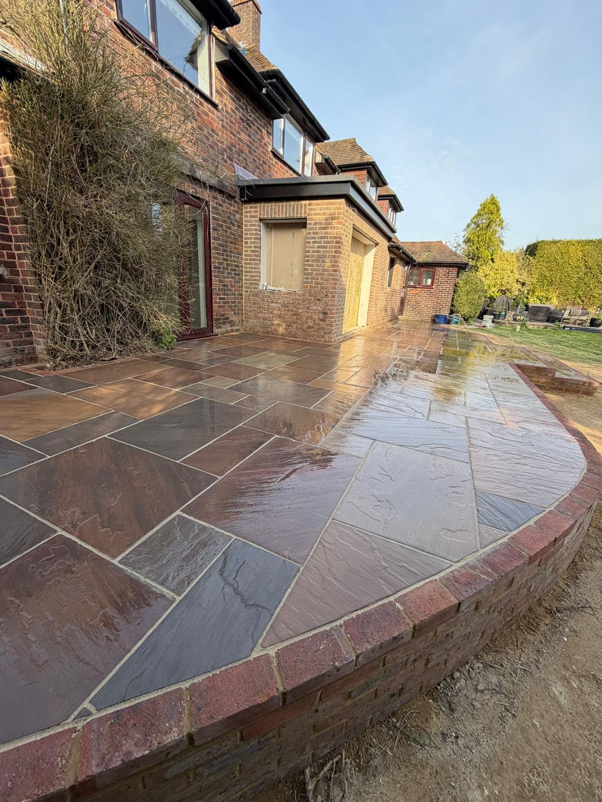 Large sandstone patio with brick wall surround
